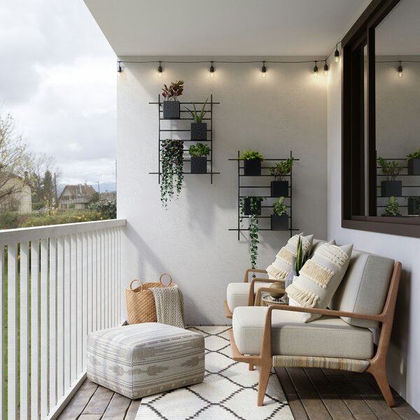 Eingerichteter Balkon mit beigem Sofa und Pflanzenregalen an der Wand